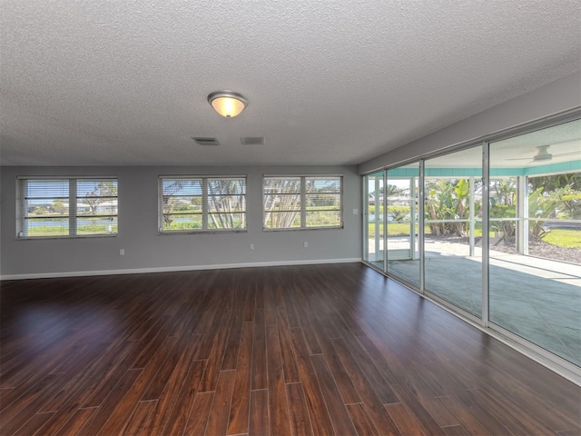 unfurnished room with a textured ceiling and dark hardwood / wood-style floors