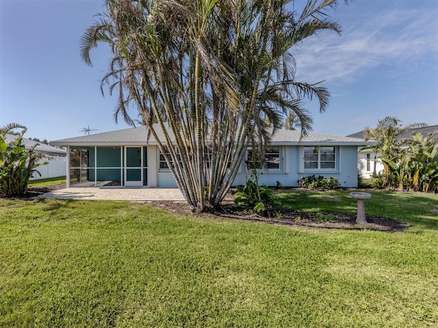 rear view of property with a lawn, a patio, and a sunroom