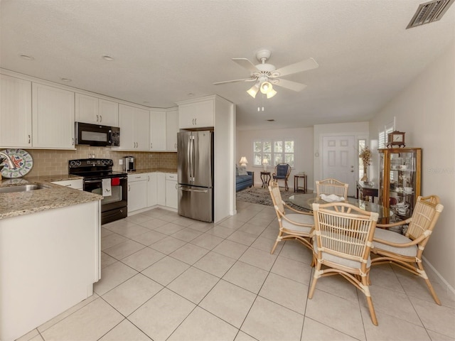 kitchen featuring black appliances, light stone counters, white cabinets, and backsplash