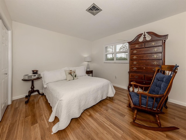 bedroom with light hardwood / wood-style floors and a closet