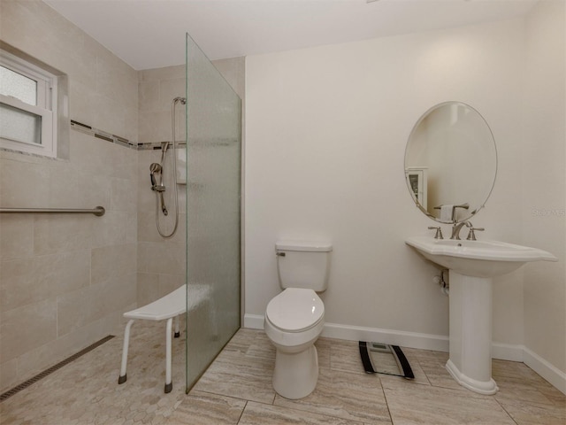 bathroom with tile patterned flooring, a tile shower, and toilet