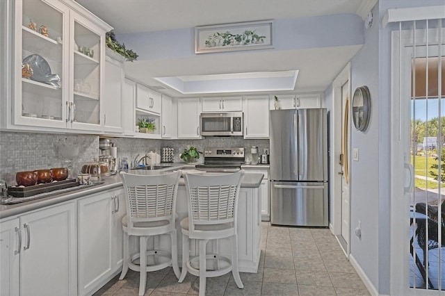 kitchen featuring white cabinets, appliances with stainless steel finishes, light tile patterned floors, and a kitchen breakfast bar