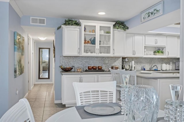 kitchen with sink, white cabinetry, light tile patterned flooring, and backsplash