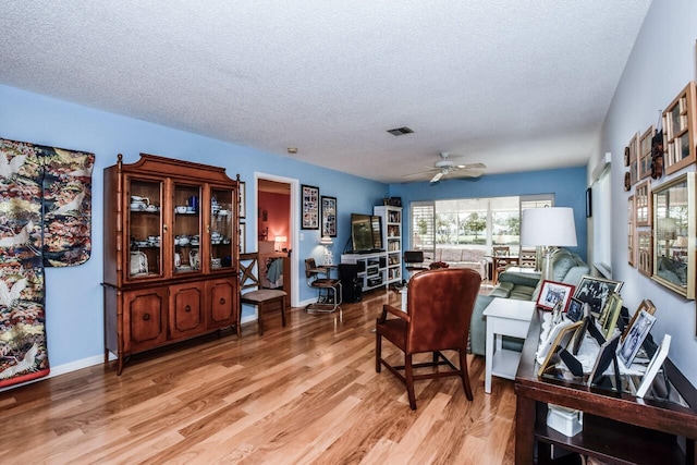 office with ceiling fan, light hardwood / wood-style floors, and a textured ceiling