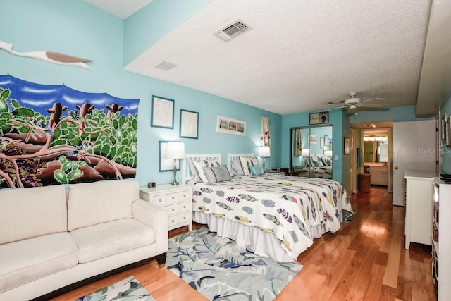 bedroom featuring ceiling fan, wood-type flooring, and a textured ceiling