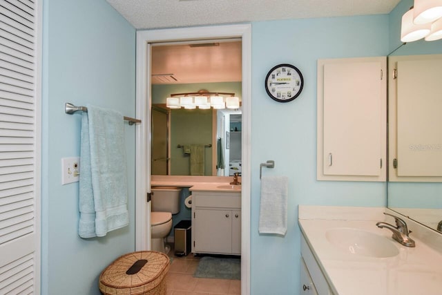 bathroom with tile patterned floors, vanity, a textured ceiling, a shower with door, and toilet