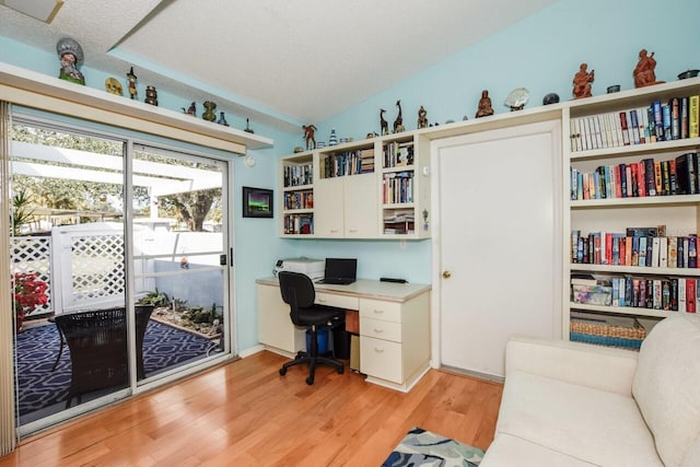 home office with light hardwood / wood-style floors, lofted ceiling, and a textured ceiling