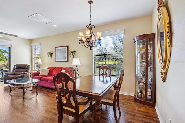 dining space with dark wood-type flooring and an inviting chandelier