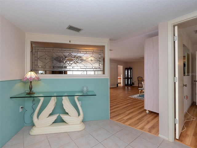 hall with a textured ceiling and tile patterned floors