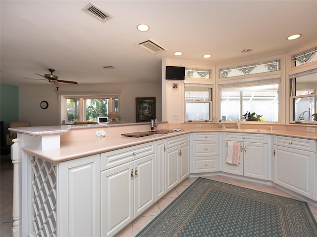 kitchen featuring sink, white cabinets, kitchen peninsula, and light tile patterned flooring