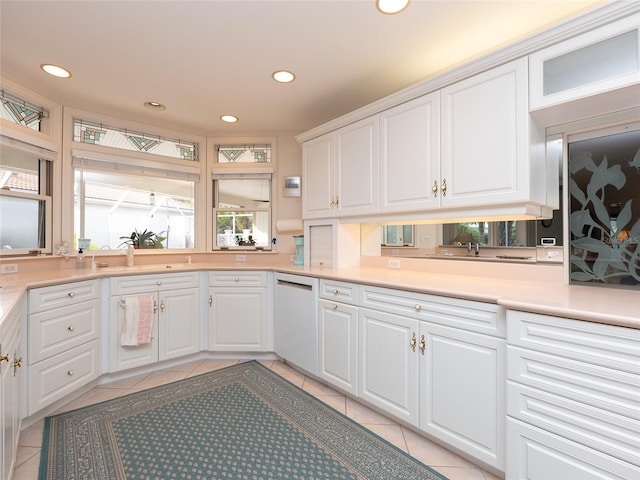 kitchen featuring sink, white cabinetry, light tile patterned floors, and white dishwasher