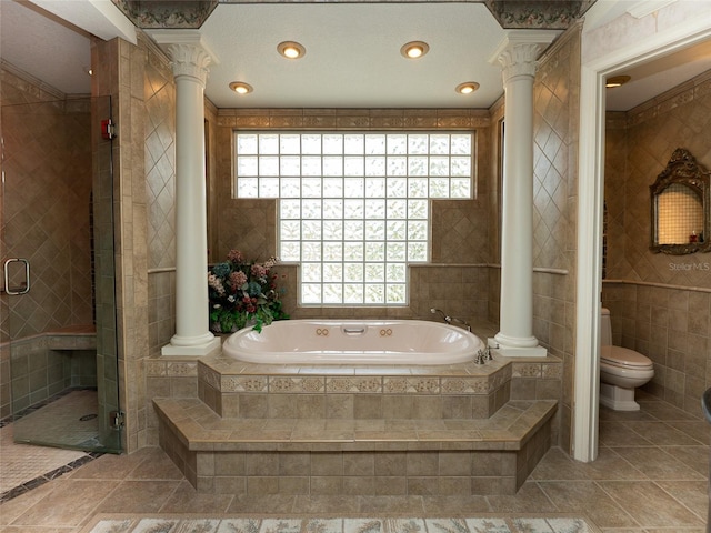 bathroom with independent shower and bath, toilet, tile walls, and ornate columns