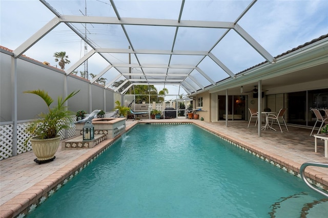 view of pool with ceiling fan, a patio area, a lanai, and pool water feature