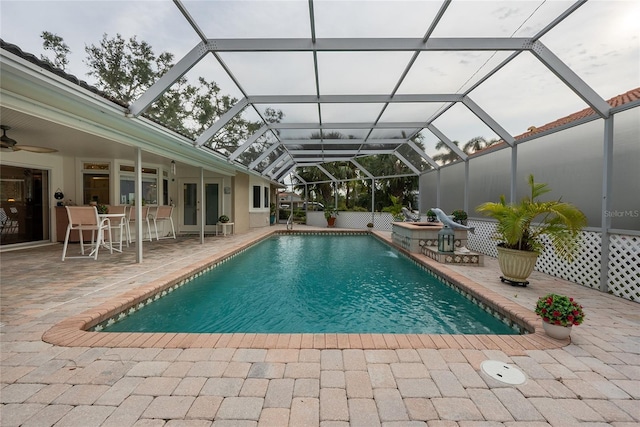 view of pool featuring a patio, glass enclosure, and ceiling fan