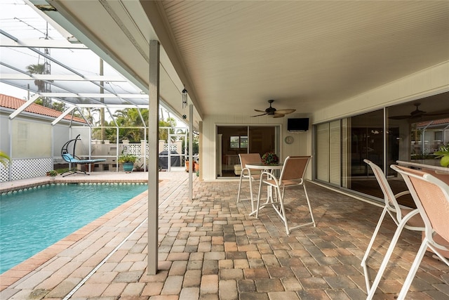 view of pool with glass enclosure, ceiling fan, and a patio area