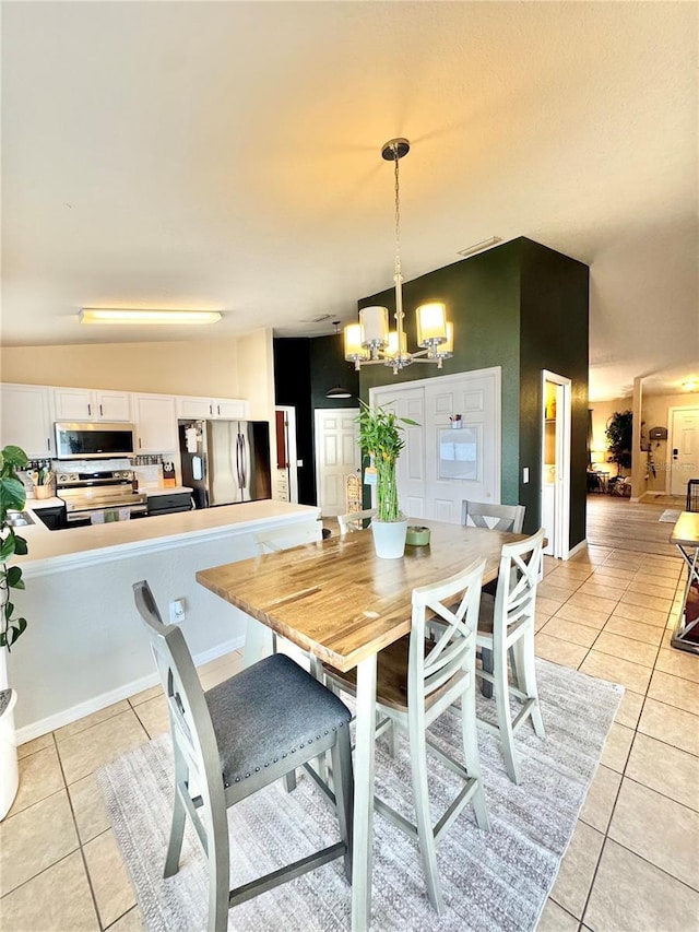 tiled dining space with lofted ceiling and an inviting chandelier