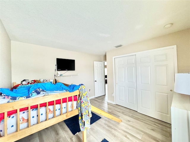 bedroom with a textured ceiling, light hardwood / wood-style flooring, and a closet