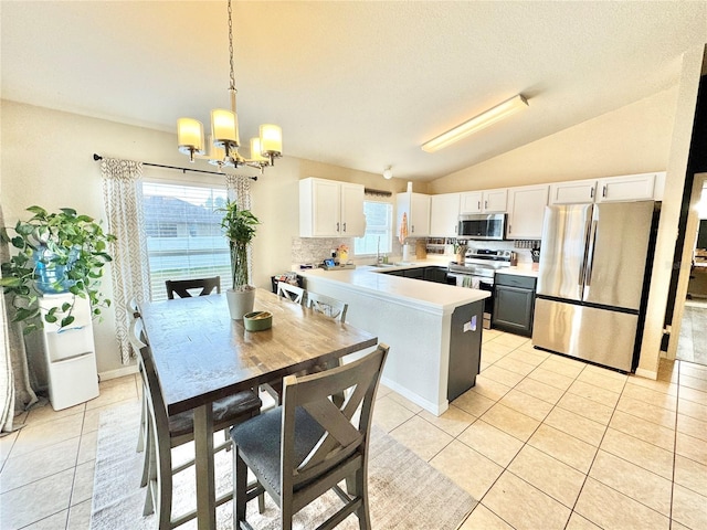 kitchen featuring pendant lighting, white cabinetry, appliances with stainless steel finishes, and vaulted ceiling