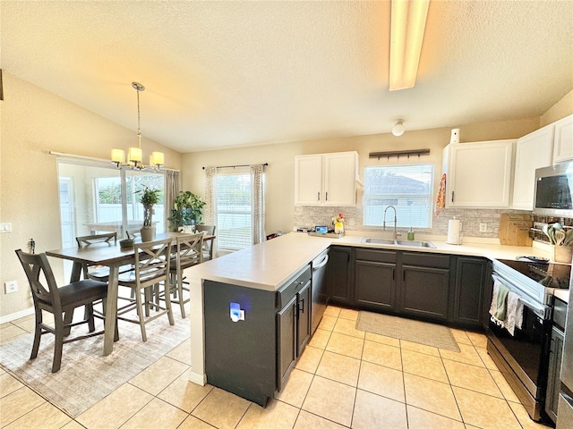 kitchen featuring pendant lighting, white cabinetry, stainless steel appliances, sink, and vaulted ceiling