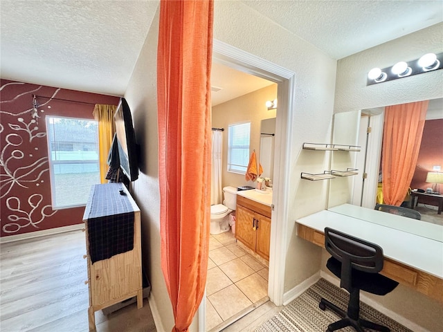 bathroom with a textured ceiling, toilet, vanity, and tile patterned flooring