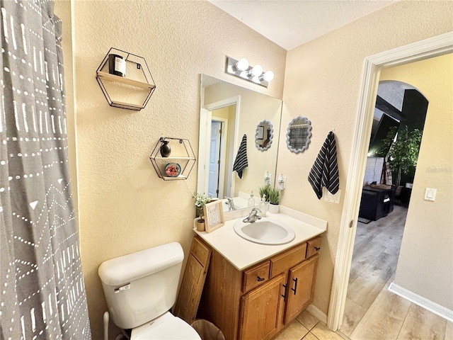 bathroom with toilet, hardwood / wood-style floors, and vanity