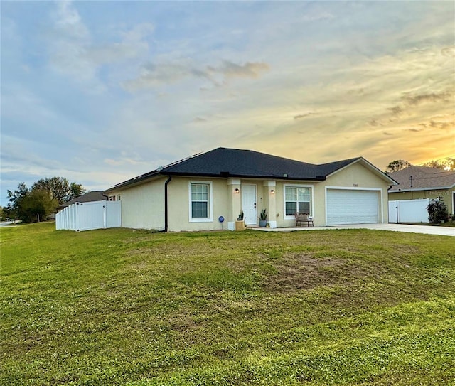 ranch-style house with a garage and a yard