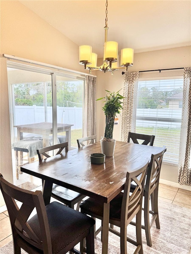 dining room with light tile patterned floors, lofted ceiling, and a chandelier