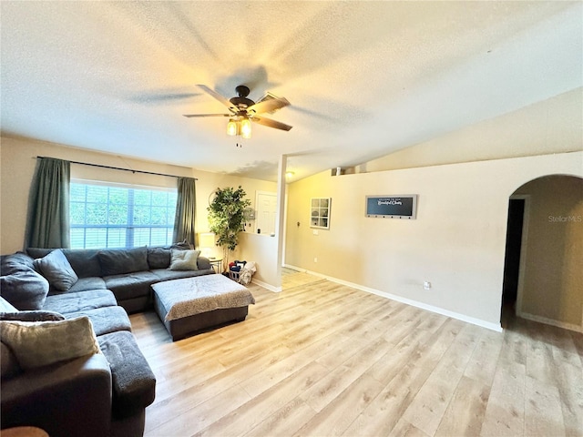 living room with lofted ceiling, a textured ceiling, and light wood-type flooring