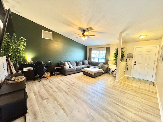 living room with lofted ceiling, a textured ceiling, light hardwood / wood-style flooring, and ceiling fan