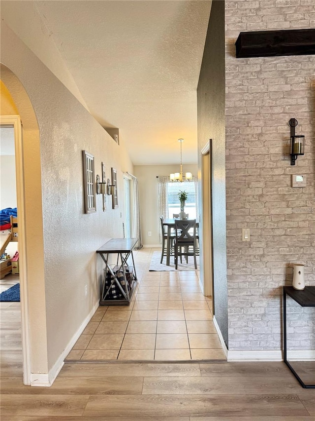 corridor featuring a chandelier, a textured ceiling, and light hardwood / wood-style flooring