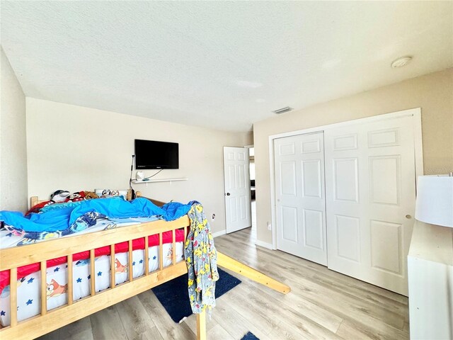 bedroom featuring light hardwood / wood-style floors, a closet, and a textured ceiling