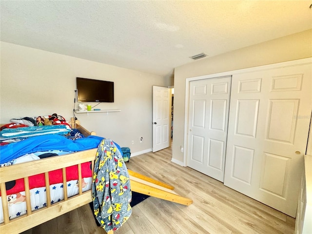 bedroom with a closet, light hardwood / wood-style flooring, and a textured ceiling