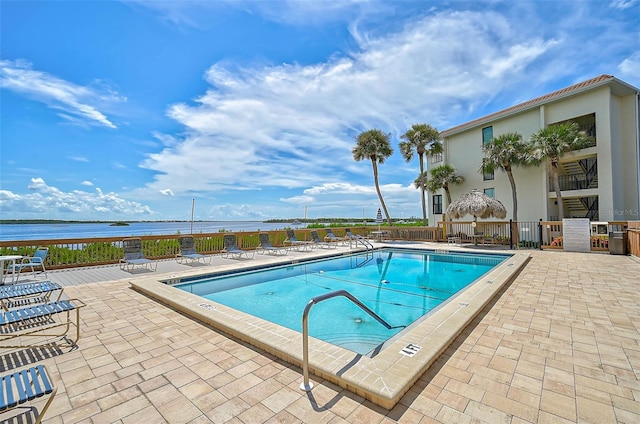 view of pool featuring a water view and a patio area