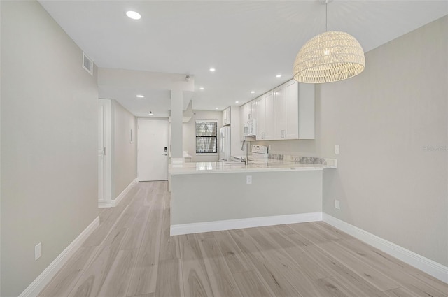 kitchen featuring white appliances, white cabinets, hanging light fixtures, kitchen peninsula, and light hardwood / wood-style flooring