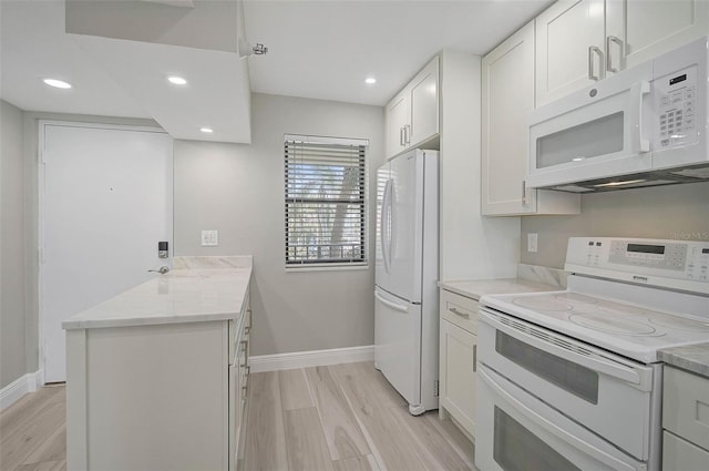 kitchen with white cabinetry, light hardwood / wood-style flooring, light stone counters, and white appliances