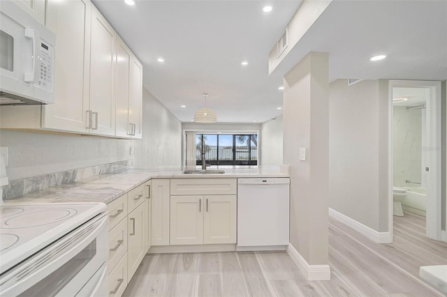 kitchen featuring kitchen peninsula, sink, white appliances, white cabinetry, and light wood-type flooring