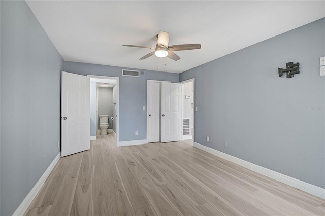 unfurnished bedroom with ceiling fan, ensuite bath, and light wood-type flooring