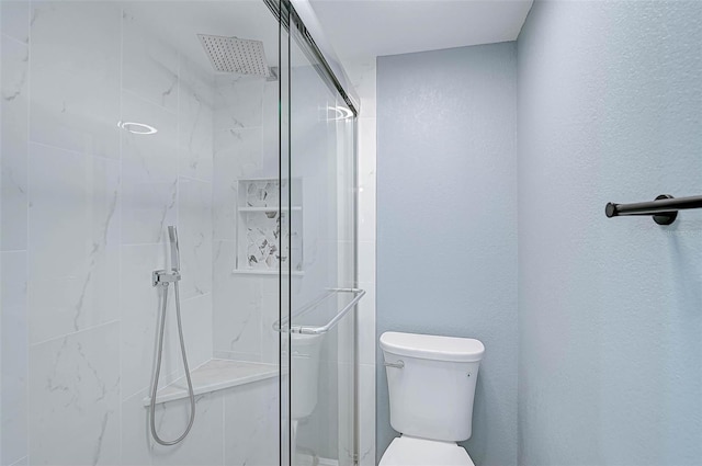 bathroom with a shower with shower door and toilet