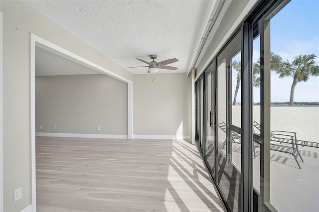 unfurnished sunroom with ceiling fan, a water view, and french doors