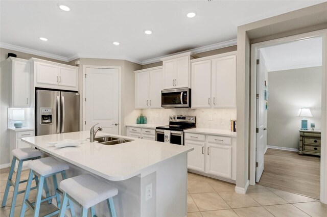 kitchen featuring a center island with sink, light tile patterned floors, white cabinetry, appliances with stainless steel finishes, and sink