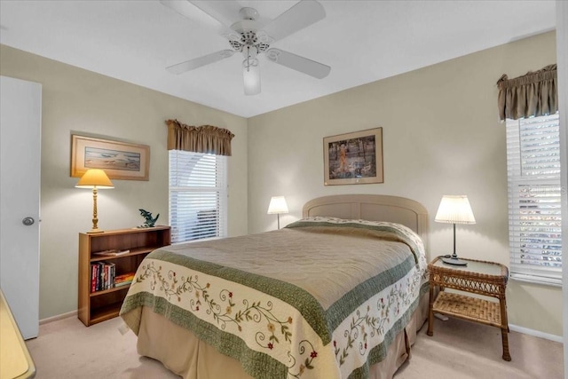 bedroom featuring multiple windows, ceiling fan, and light colored carpet