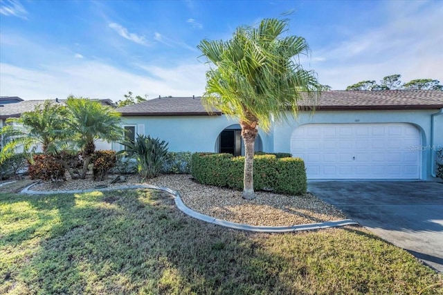 view of front of home with a front yard, an attached garage, driveway, and stucco siding