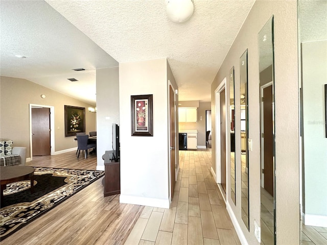 hallway featuring lofted ceiling and a textured ceiling