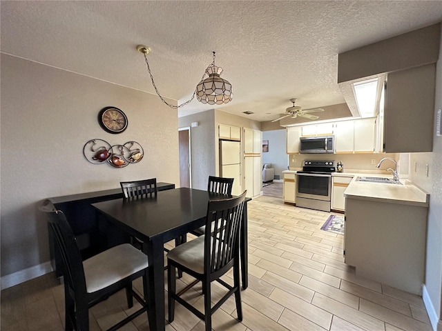 dining area with a textured ceiling, ceiling fan, and sink