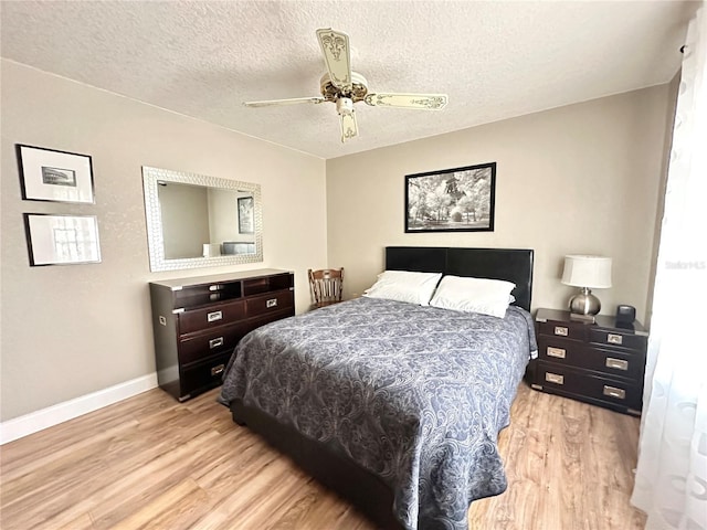 bedroom with ceiling fan, light wood-type flooring, and a textured ceiling