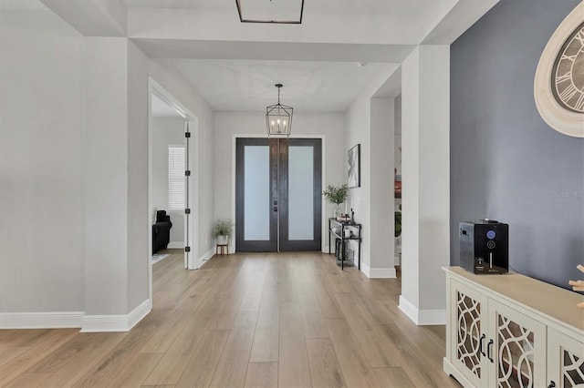 entrance foyer featuring french doors, light hardwood / wood-style flooring, and a notable chandelier