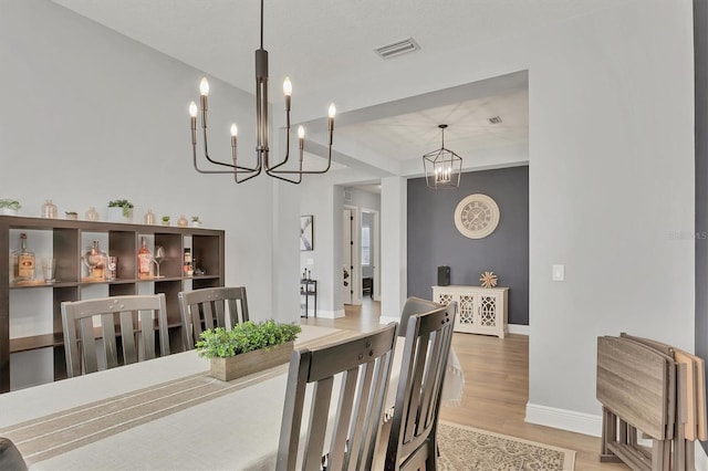 dining space with hardwood / wood-style flooring and a notable chandelier