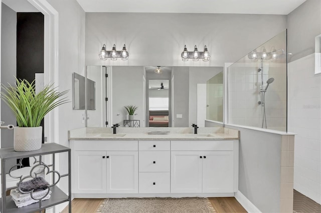 bathroom featuring a tile shower, vanity, hardwood / wood-style flooring, and ceiling fan