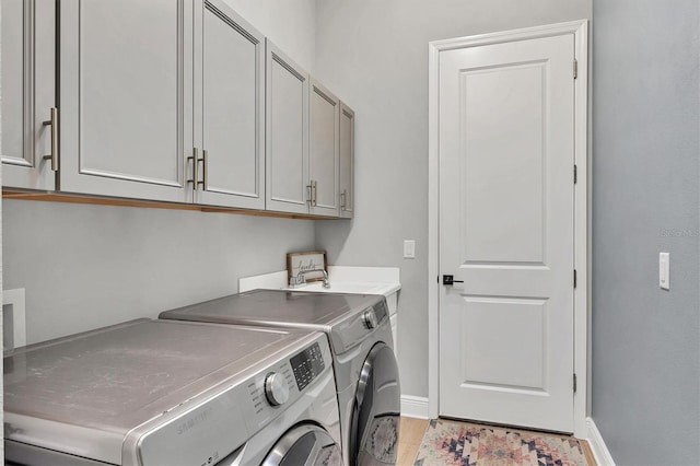 clothes washing area with cabinets, washer and dryer, and sink