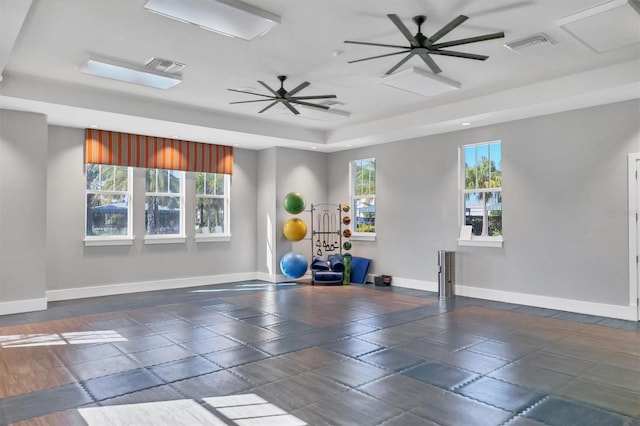 workout area featuring ceiling fan and a tray ceiling